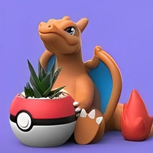 May include: A ceramic planter shaped like a cartoon orange and red dragon holding a red and white Pokeball planter with a green succulent plant inside.