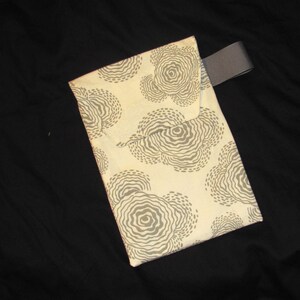 Puede incluir: Una bolsa de tela de color crema con una correa gris. La bolsa tiene un patr&oacute;n de c&iacute;rculos grises y blancos.