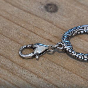 K&ouml;nnte beinhalten: Eine wei&szlig;e Keramik-Tasse mit schwarzem Henkel und dem Text "But First, Coffee" in schwarzer, fetter Schrift. Die Tasse steht auf einer wei&szlig;en Oberfl&auml;che.