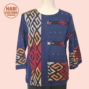 May include: A blue long-sleeve shirt with a round neckline. The shirt features a geometric pattern in red, yellow, and white. The brand logo "HABI CULTURE" is visible in the upper left corner.