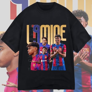May include: Black t-shirt with a gold graphic of the word "LAMICE" and images of four soccer players wearing Barcelona jerseys. The players are all young men with dark hair and are wearing the team's signature blue and red colors.