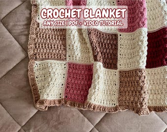 May include: A crocheted blanket with a patchwork design in shades of brown, pink, and white. The blanket is made with a textured stitch and has a fringed edge. The text "CROCHET BLANKET ANY SIZE | PDF + VIDEO TUTORIAL" is displayed on the blanket.