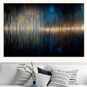 May include: Abstract sound wave art print in gold and white against a dark blue and black backdrop. The artwork is displayed above a white sofa with striped cushions and a blue vase, creating a modern aesthetic.