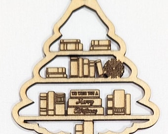 May include: Wooden Christmas tree ornament with a bookshelf design. The ornament features a star on top and shelves filled with books. The bottom shelf has a sign that reads "We wish you a Merry Christmas".