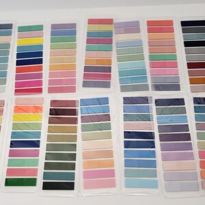 May include: A collection of color swatches in various shades, arranged in rows. The swatches are in a range of colors, including blues, greens, pinks, oranges, and browns. Each swatch is rectangular and appears to be made of fabric or paper.