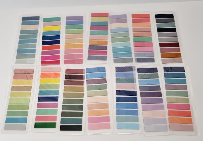 May include: A collection of color swatches in various shades, arranged in rows. The swatches are in a range of colors, including blues, greens, pinks, oranges, and browns. Each swatch is rectangular and appears to be made of fabric or paper.