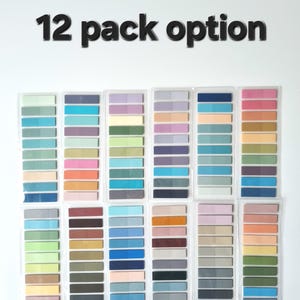 May include: A collection of twelve packs of colorful sticky notes, each with a gradient of shades. The notes are arranged in rows, showcasing a variety of hues including blues, greens, pinks, and purples. The text "12 pack option" is displayed above the notes.