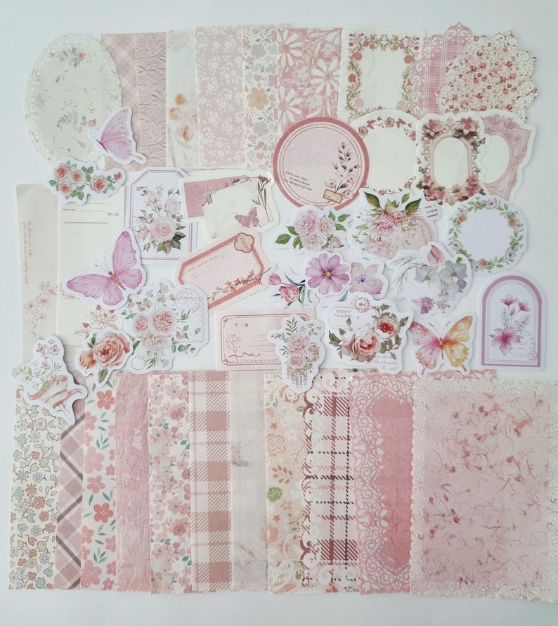 Op de afbeelding: Een verzameling roze en wit scrapbookpapier, stickers en versieringen. De set bevat bloempatronen, vlinders, labels en frames. Het kleurenpalet is zacht en vrouwelijk, perfect voor knutsel- en journalingprojecten.