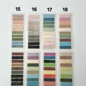 May include: A collection of color swatches, each in a clear plastic sleeve, arranged in rows and columns. The swatches display a variety of colors, including shades of pink, green, blue, and brown. Numbers 15 through 22 are printed above each column.