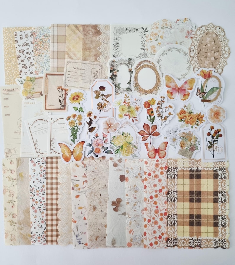 Op de afbeelding: Een verzameling papier en stickers in vintage-stijl. De collectie bevat bloemen- en vlinderstickers, papier met patronen en decoratieve frames in beige, bruin en oranje tinten. Ideaal voor scrapbooking- en knutselprojecten.