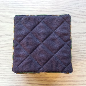 May include: A brown quilted fabric pouch with a green, yellow, and orange patterned border.