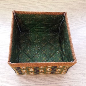 May include: A green and brown fabric storage box with a quilted interior and a pattern of small bears on the exterior.