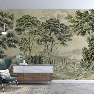 Könnte beinhalten: Ein Aquarell-Wandbild, das eine ruhige Landschaft mit Bäumen, Hügeln und einem bewölkten Himmel in Grün- und Grautönen darstellt. Ein moderner Stuhl, ein Schrank und ein Teppich befinden sich im Vordergrund und schaffen ein stimmiges Innendesign.