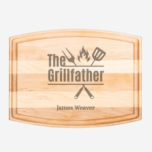 May include: A rectangular wooden cutting board with a light wood grain pattern. The text "The Grillfather" is engraved in the center, with grilling tools and the name "James Weaver" below. The board has a juice groove.