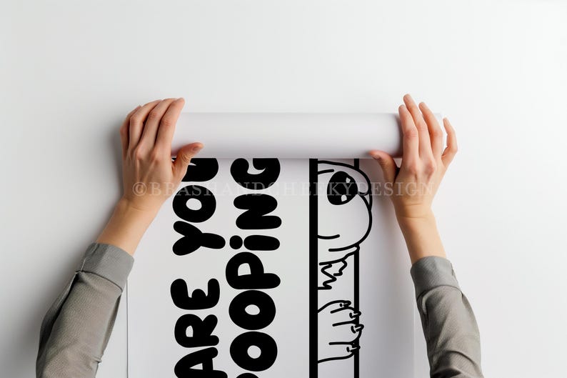 May include: A white poster with black text and a cartoon alien illustration is being unrolled. The text reads "Are You Kidding?" The alien is peeking out from behind a vertical line. The poster is held by two hands.