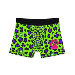 Puede incluir: Bóxers con estampado de leopardo verde neón, con manchas moradas y una huella de pata rosa. La cintura es negra. Los bóxers tienen un panel central con un estampado de leopardo más pequeño.