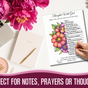 May include: A white notebook with a gold pen, a laptop, and a pink dish with paper clips are on a white surface. A page with the text "Thoughts With God" and colourful floral illustrations is being written on with a pencil. Pink flowers are in the background.