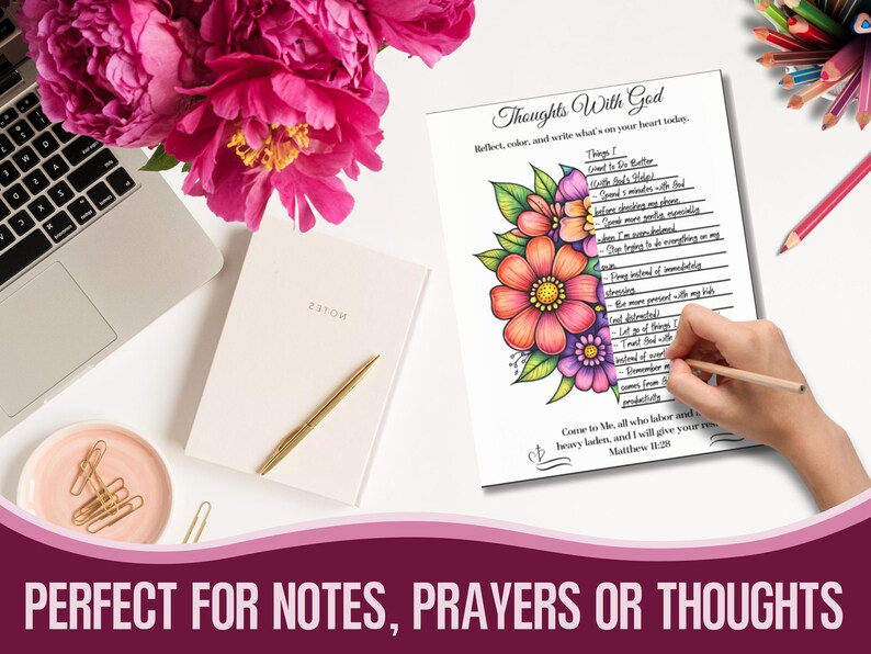 May include: A white notebook with a gold pen, a laptop, and a pink dish with paper clips are on a white surface. A page with the text "Thoughts With God" and colourful floral illustrations is being written on with a pencil. Pink flowers are in the background.