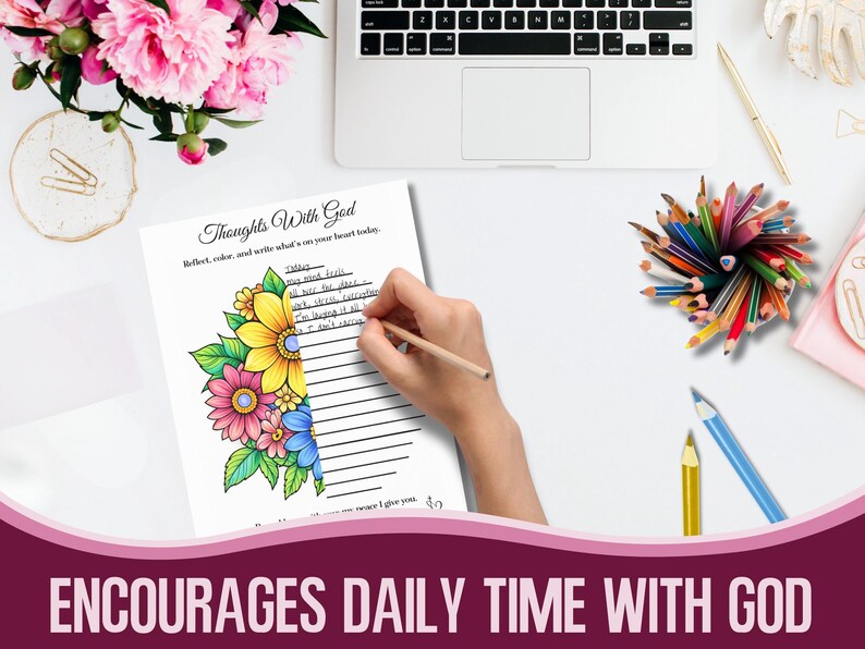 May include: A journal page titled "Thoughts With God" with floral illustrations. A hand holding a pencil is writing on the page. The page is surrounded by coloured pencils, a laptop, and pink flowers.