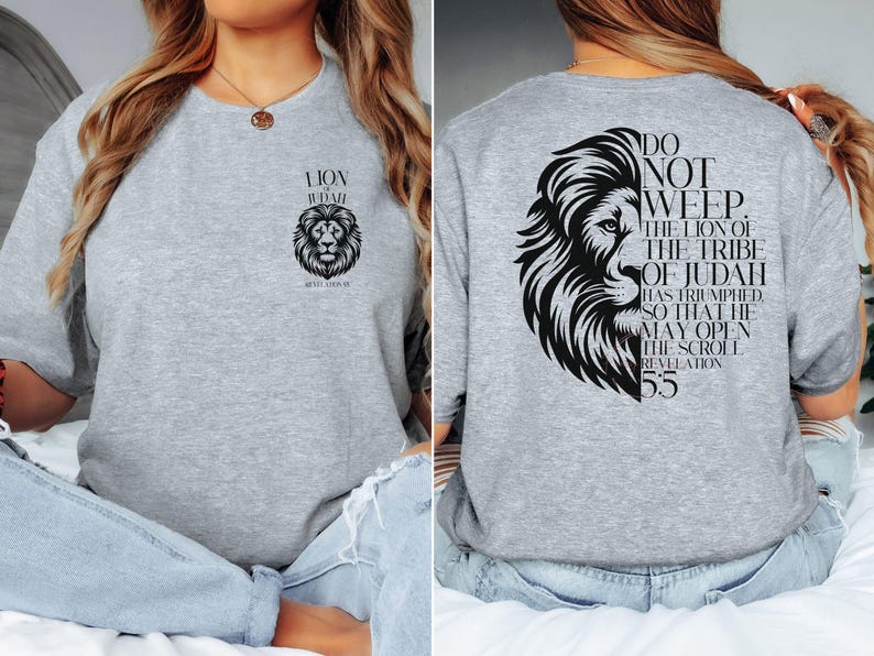 May include: A light gray crew neck t-shirt featuring a black lion graphic and text. The front of the shirt displays a lion's head and the words "LION OF JUDAH". The back of the shirt has a lion's head and the text "DO NOT WEEP. THE LION OF THE TRIBE OF JUDAH".