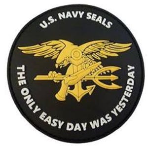 May include: A black and gold round patch with the U.S. Navy Seals logo. The logo features a bald eagle with wings spread, holding a pistol and trident. The text "U.S. NAVY SEALS" is written in white above the logo, and "THE ONLY EASY DAY WAS YESTERDAY" is written in white below the logo.