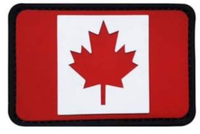 May include: A red rectangular patch with a white maple leaf in the center. The patch has a black border.