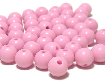 May include: A large pile of pink round plastic beads. The beads are smooth and shiny.