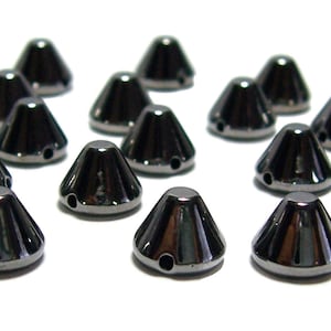 May include: A group of 18 black cone-shaped rhinestones with a hole in the center.