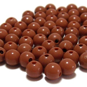 May include: A pile of 6mm brown plastic beads. The beads have a hole in the center.