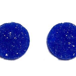 May include: A pair of blue round stud earrings with a sparkly, textured surface.