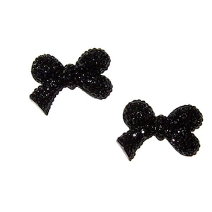 May include: Two black rhinestone bow embellishments. Each bow is made of small black rhinestones and has a flat back.