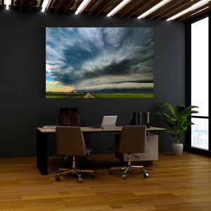 Op de afbeelding: Een groot canvasdoek met een dramatische stormwolkformatie boven een landelijk landschap. De afbeelding toont een lange, rechte weg die naar de horizon leidt, met groene velden aan weerszijden. De lucht is gevuld met wervelende donkere wolken.