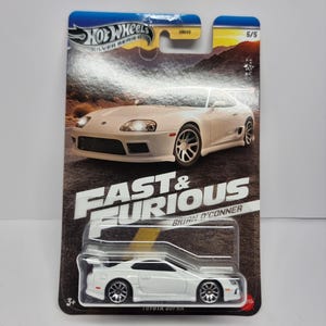 May include: A white Toyota Supra die-cast model car from the Hot Wheels Silver Series, packaged on a Fast & Furious card. The card features images of the car and the text "FAST & FURIOUS" and "Brian O'Conner".