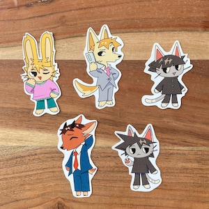 May include: Five animal character stickers with different expressions. The stickers are on a wooden surface. The characters are a rabbit, a fox, a cat, a deer, and another cat. The characters are all wearing clothes and have different facial expressions.