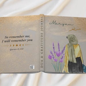 May include: Open journal with a gold and gray cover. The left side has the text "So remember me, I will remember you" and "Quran 2:152". The right side features an illustration of a person in a hijab, lavender flowers, and the name "Maryam".