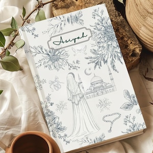 May include: A white journal with a blue-grey floral and architectural design. The cover displays the name "Asiyah" in a green frame, a mosque illustration, and a veiled woman.