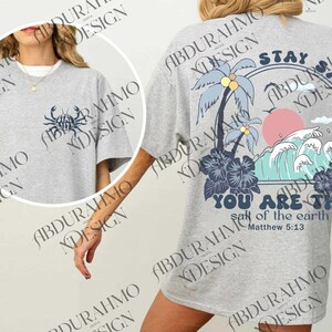 a woman wearing a gray shirt with a palm tree on it