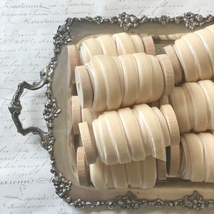 May include: A silver tray filled with spools of ivory satin ribbon. The ribbon is wound around wooden spools and is arranged in a neat and organized fashion.