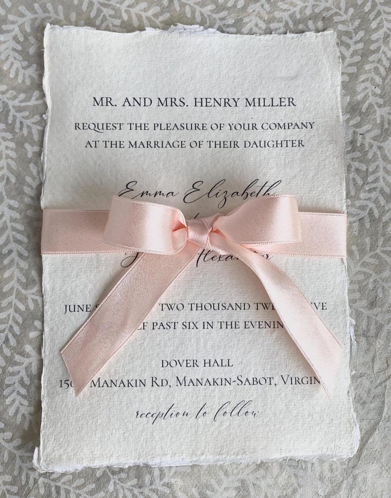 K&ouml;nnte beinhalten: Eine Hochzeitseinladung mit einem rosa Band darum gebunden. Die Einladung ist auf strukturiertem Papier gedruckt und lautet "MR. AND MRS. HENRY MILLER REQUEST THE PLEASURE OF YOUR COMPANY AT THE MARRIAGE OF THEIR DAUGHTER Emma Elizabeth Hexa TWO THOUSAND TW F PAST SIX IN THE EVENIN VE DOVER HALL 150 MANAKIN RD, MANAKIN-SABOT, VIRGIN reception to follow"