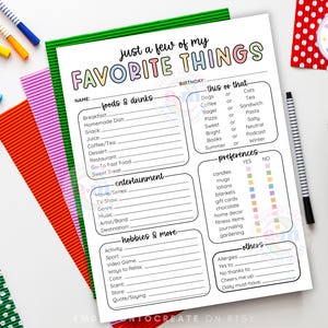 May include: A printable "Favorite Things" worksheet with a green border, featuring fill-in sections for foods, entertainment, hobbies, and preferences. The text is in a colorful, playful font. Colorful pens and paper are arranged around the worksheet.