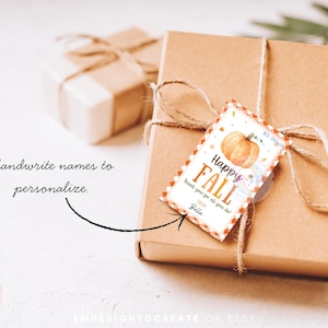 May include: A brown gift box tied with twine, featuring a fall-themed tag with a pumpkin illustration and the words "Happy Fall." The tag includes space to personalise with a name. Another gift box is visible in the background.