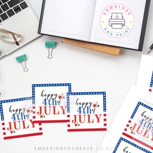 May include: White desk with a laptop, glasses, and stationery. Several square tags with a red, white, and blue design that says "Happy 4th of July". A notebook with a "Download and Print" graphic is open.
