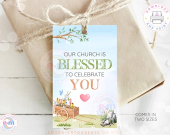 May include: A gift tag with the text "OUR CHURCH IS BLESSED TO CELEBRATE YOU". The tag features a watercolor design of a wooden cart filled with flowers, a pink heart, and a small garden scene. The tag is tied to a wrapped gift.