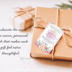 Puede incluir: Una caja de regalo marr&oacute;n con una etiqueta del D&iacute;a de la Madre. La etiqueta presenta dise&ntilde;os florales y el texto "Happy Mother's Day". La caja est&aacute; atada con hilo y se encuentra sobre una superficie blanca. El texto dice "Escribe el nombre para un toque personal y c&aacute;lido."