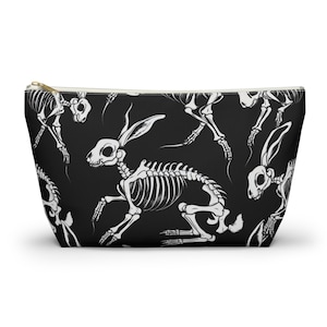 May include: Black zippered pouch with a white repeating pattern of rabbit skeletons.