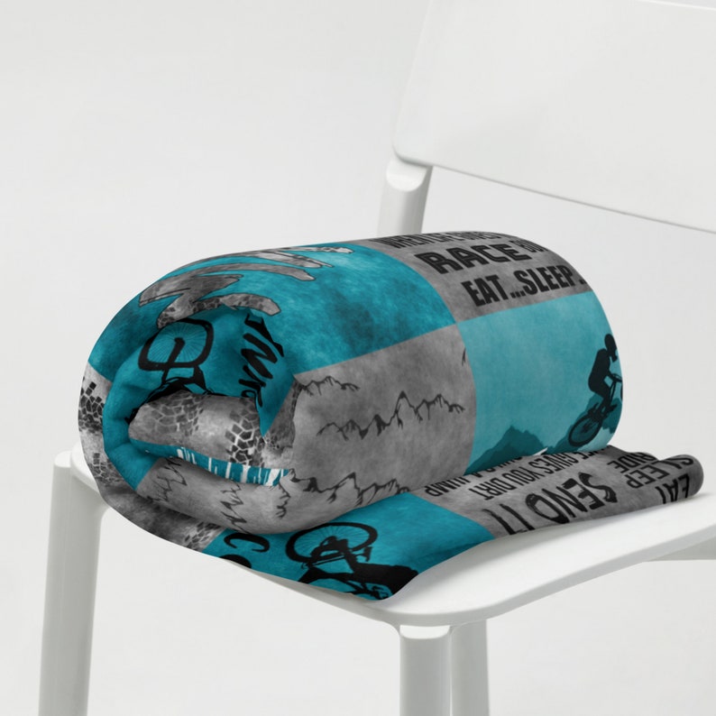 K&ouml;nnte beinhalten: Eine blaue und graue Fleece-Decke mit einem Mountainbike-Design und dem Text "Send it, sleep, eat... race, repeat".