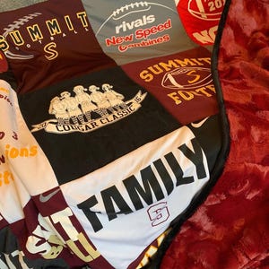 May include: A patchwork quilt made from various athletic t-shirts featuring logos and text including Summit Football, Rivals New Speed Combines, Cougar Classic 2016, and Family. The quilt has a deep red, textured plush backing with a black border.