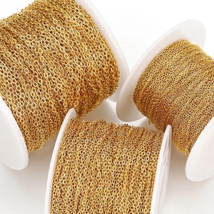 May include: Three spools of gold chain, each wound around a white plastic spool. The chain is a fine, delicate, and uniform chain.