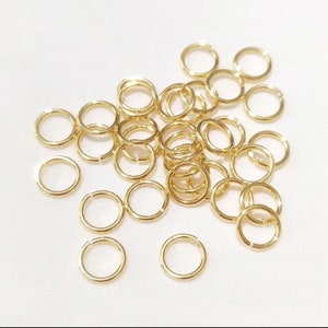 May include: A large quantity of gold jump rings. The rings are small and circular, perfect for jewelry making or crafting.