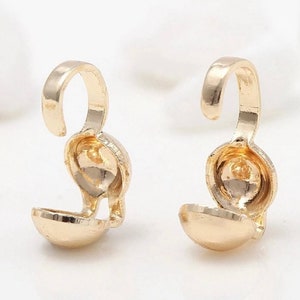 Peut inclure: Deux fermoirs en métal doré avec un crochet à une extrémité et une boule ronde creuse à l'autre. Les fermoirs sont conçus pour être utilisés pour la fabrication de bijoux.
